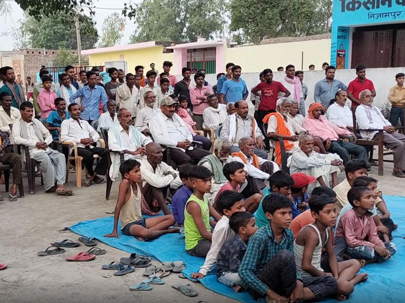A photograph showing men and boys from Terai listening to a presentation about the project
