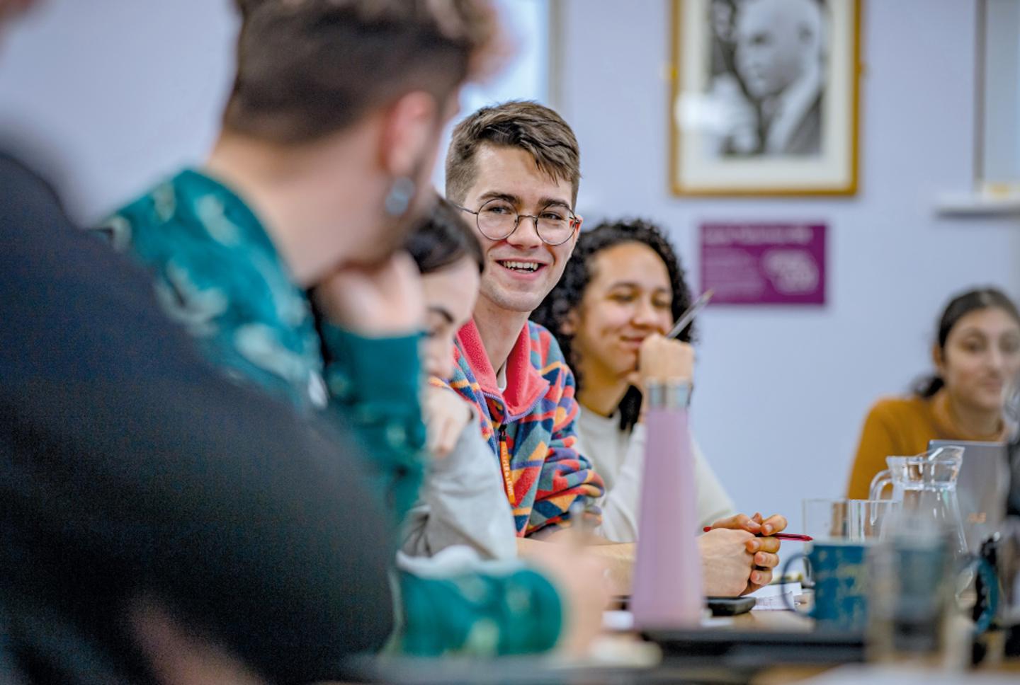 A photo showing young people sitting in a board room while holding a discussion